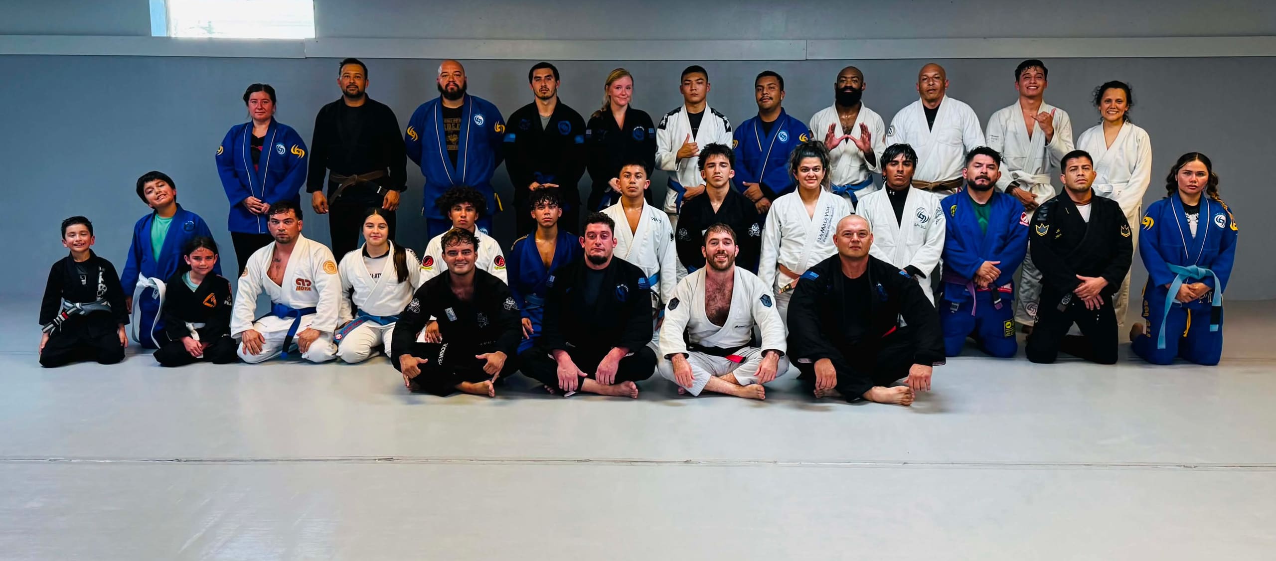 The SPI Jiu Jitsu team on the mats after class — kids, teens and adults in gis, every belt from white to black.